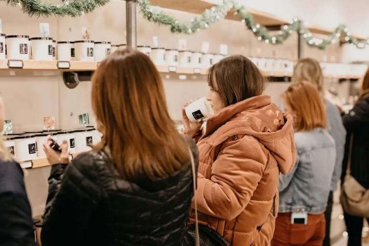 People browsing jars on shelves in a well-lit store with holiday decorations.